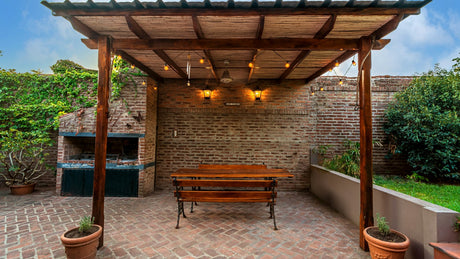 Wooden pergola over a brick backyard patio with a picnic table